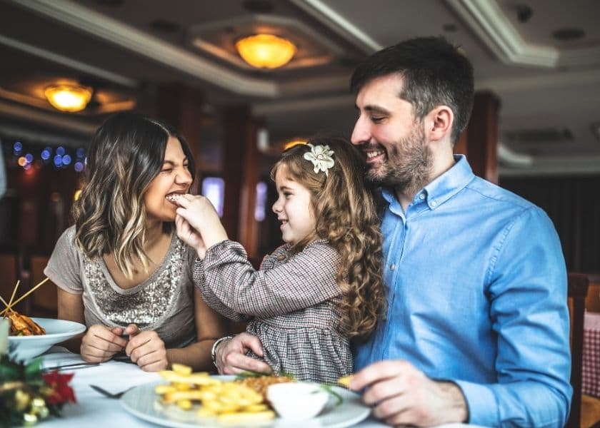 A family seated together at a restaurant and sharing bites from a meal. A family seated together at a restaurant and sharing bites from a meal.
