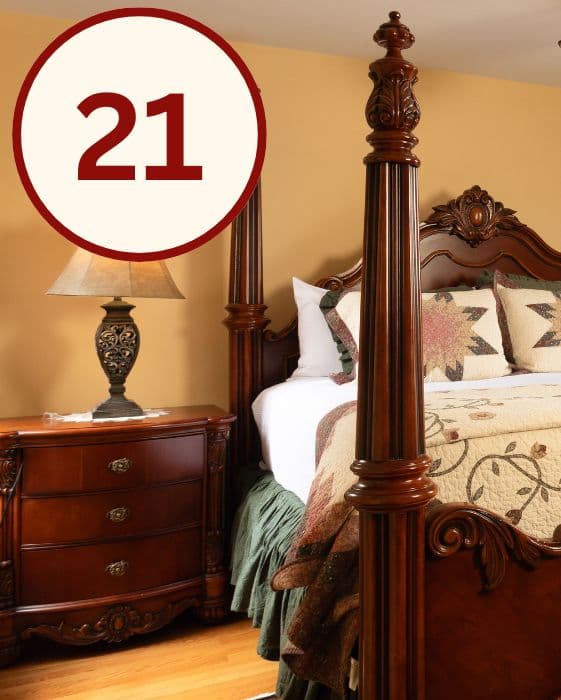 A cozy bedroom featuring a four-poster bed, decorative pillows, a bedside lamp, and a wooden nightstand.