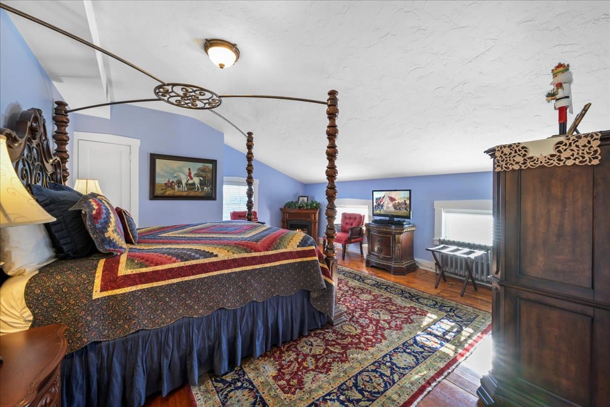 Cozy bedroom featuring a four-poster bed, decorative quilt, and rich wooden furnishings.